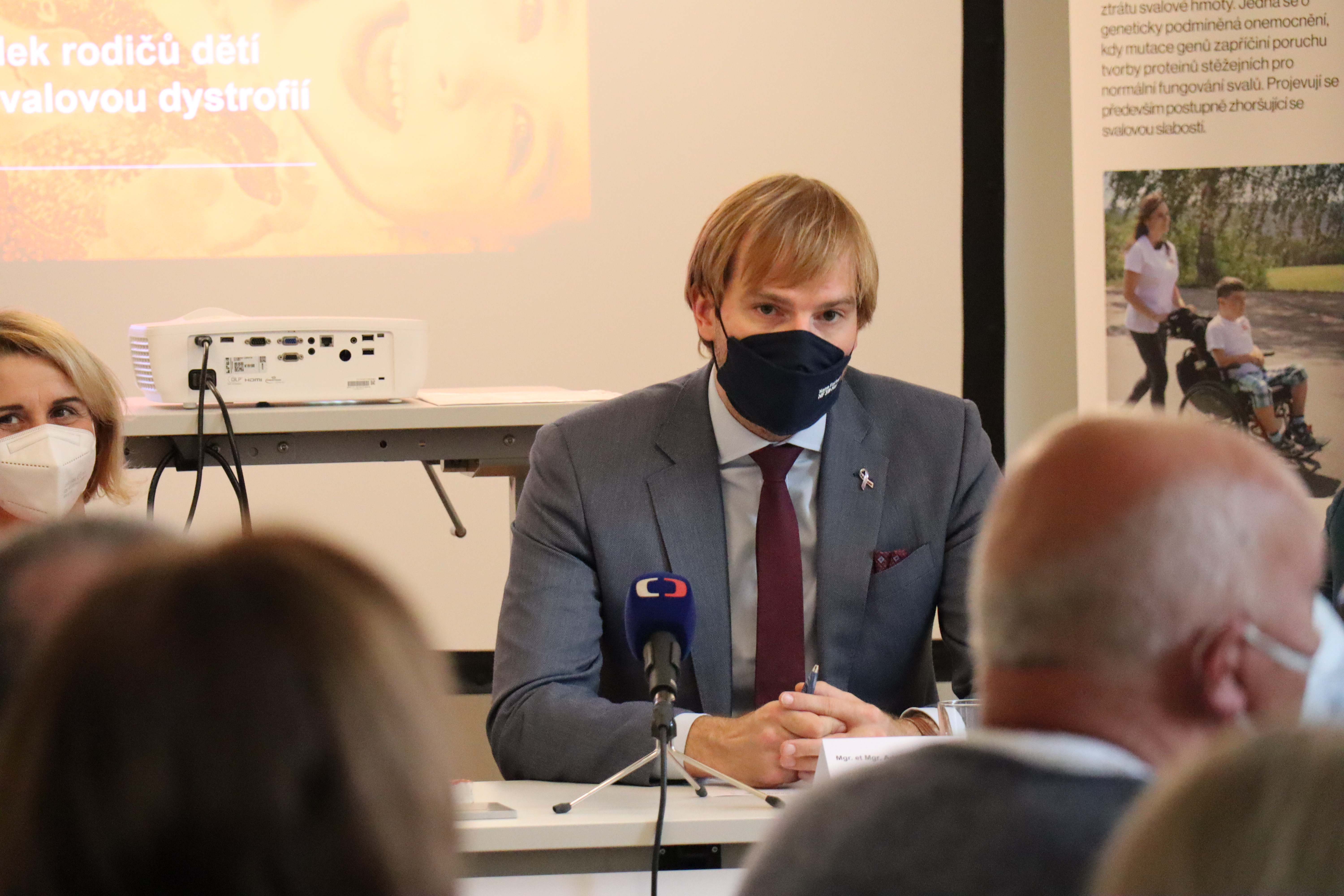 Fotografie ministra zdravotnictví Adama Vojtěcha s respirátorem na panelu řečníků.